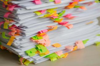 Stack of papers marked with colorful sticky tabs by Tanja Tepavac courtesy of Unsplash.