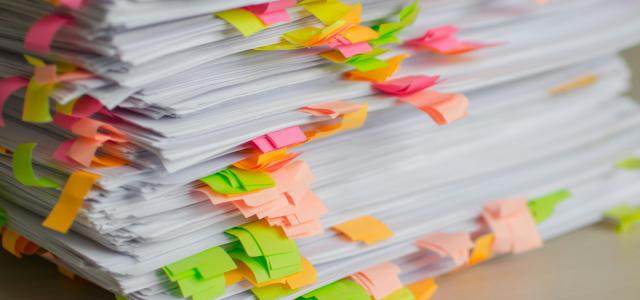 Stack of papers marked with colorful sticky tabs by Tanja Tepavac courtesy of Unsplash.
